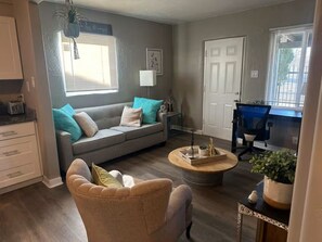 Ein Wohnzimmer mit Sofa, Sessel, Couchtisch und einer Tür.