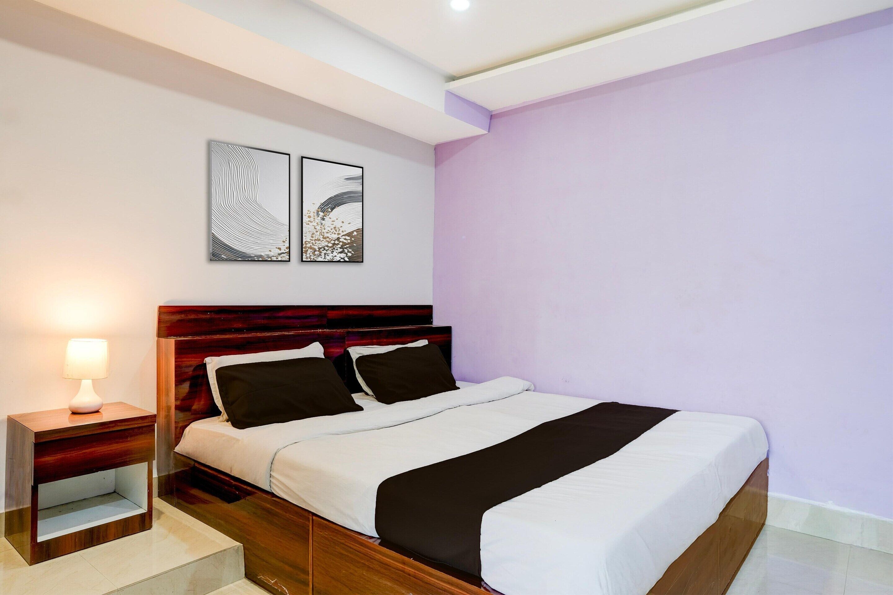 A bedroom with a wooden bed, a nightstand with a lamp, and two wall-mounted artworks.