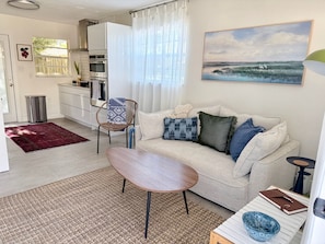 Ein modernes Wohnzimmer mit Sofa, Couchtisch, Esstisch und Küchenzeile.