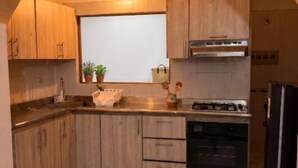 A kitchen with wooden cabinets, a gas stove, a refrigerator, and a window with a view.