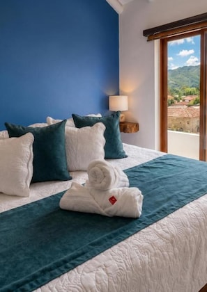 A neatly made bed with a blue and white duvet, pillows, and a folded towel. - Casa Hotel Cenit (Villa de Leyva)