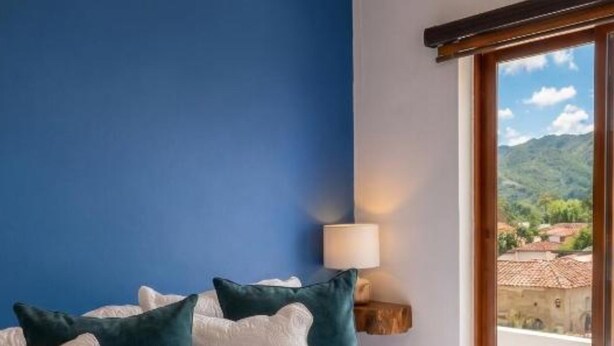 A neatly made bed with a blue and white duvet, pillows, and a folded towel.