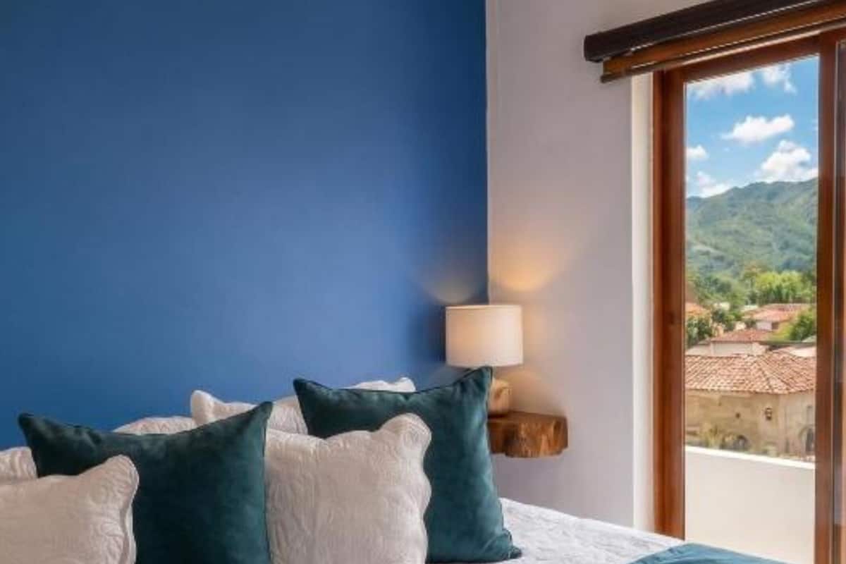 A neatly made bed with a blue and white duvet, pillows, and a folded towel.