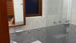 A bathroom with a toilet, sink, and glass shower enclosure.