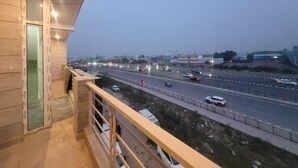 En balkon med udsigt til en trafikeret motorvej og fjerne bygninger.