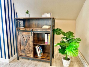 Une bibliothèque en bois au design rustique, une plante en pot et des livres.