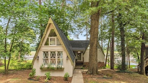 A house with a steep gable roof, a front porch, and a pathway leading to the entrance.