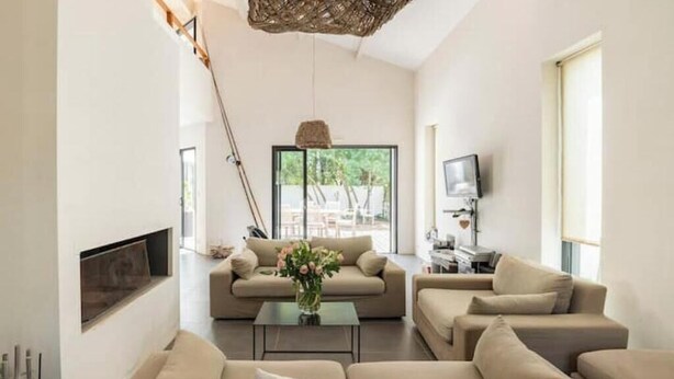 Un salon moderne comprenant un canapé, une table basse, un téléviseur et une grande fenêtre.