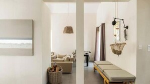 Un salon minimaliste comprenant un canapé, une petite table, un luminaire suspendu et un panier fixé au mur.
