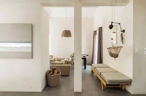 Ein minimalistisches Wohnzimmer mit Sofa, einem kleinen Tisch, einer Pendelleuchte und einem an der Wand befestigten Korb.