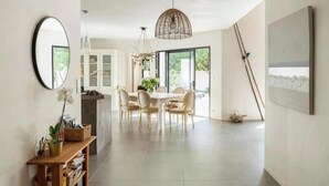 Un vaste espace dédié à la salle à manger, avec une table ronde et des chaises, un luminaire suspendu et une grande fenêtre offrant une vue sur l’extérieur.