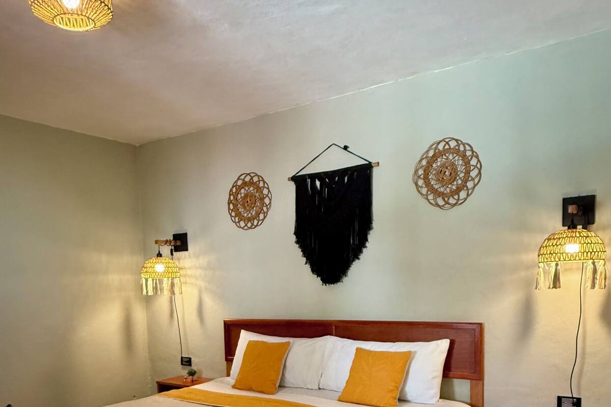 A neatly made bed with a patterned bedspread, a wooden headboard, and two bedside lamps.