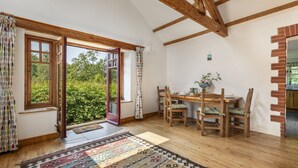 Un comedor con muebles de madera, un tapete estampado y vista a través de una puerta abierta.