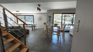Un interno moderno con una scala, zona pranzo e ampie finestre.
