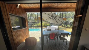 Un terrazzo in legno con tavolo e sedie, una piscina e un'area coperta con tavolo e sedie.