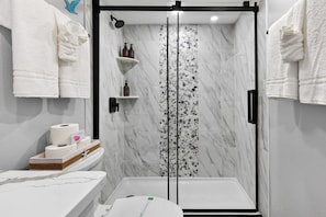 Ein Badezimmer mit Dusche, Toilette und Handtuchhalter.