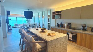 A modern kitchen with a central island, bar stools, and a view of the ocean. - Waterfront penthouse in Yucalpetén Resort Marina (Progreso)