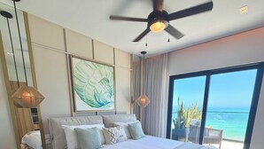 A bedroom with a large bed, a ceiling fan, a bedside table, a floor lamp, a framed picture, and a view of the ocean through a large window. - Waterfront penthouse in Yucalpetén Resort Marina (Progreso)