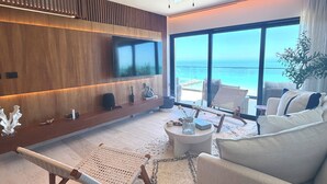 A modern living room with a large TV, a ceiling fan, a sofa, and a view of the ocean. - Waterfront penthouse in Yucalpetén Resort Marina (Progreso)
