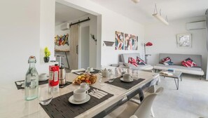 Ein moderner Essbereich mit einem für das Frühstück gedecktem Tisch, einer Couch und abstrakter Kunst an den Wänden.