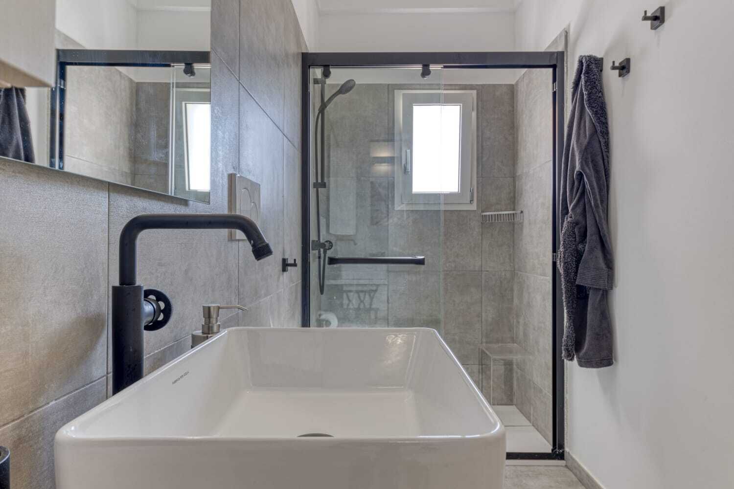 Ein modernes Badezimmer mit einem großen rechteckigen Waschbecken, einer Duschkabine aus Glas und einem Handtuchhalter.