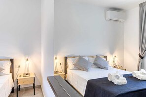 Ein Hotelzimmer mit Bett, Nachttischen, einer Bank, einer Klimaanlage und Handtüchern.