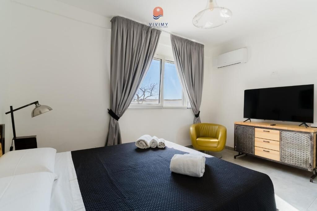 A hotel room with a bed, a television, a desk, a chair, and curtains.