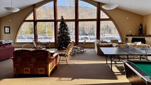 Un'ampia stanza con una grande finestra ad arco, un tavolo da ping pong e un albero di Natale.