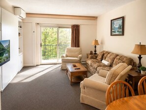 Ein Zimmer mit Sofa, Sessel, Couchtisch und Fernseher.
