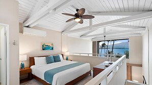 A bedroom with a bed, a nightstand, a lamp, a ceiling fan, and a view of the ocean. - Oceanview 2BR/2BA Condo w/ Pool, A/C, Balcony & Beach Access – Maalaea Kai 403 (Wailuku)