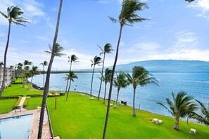 Ein Resort mit Pool, Rasen, Palmen und Meerblick.