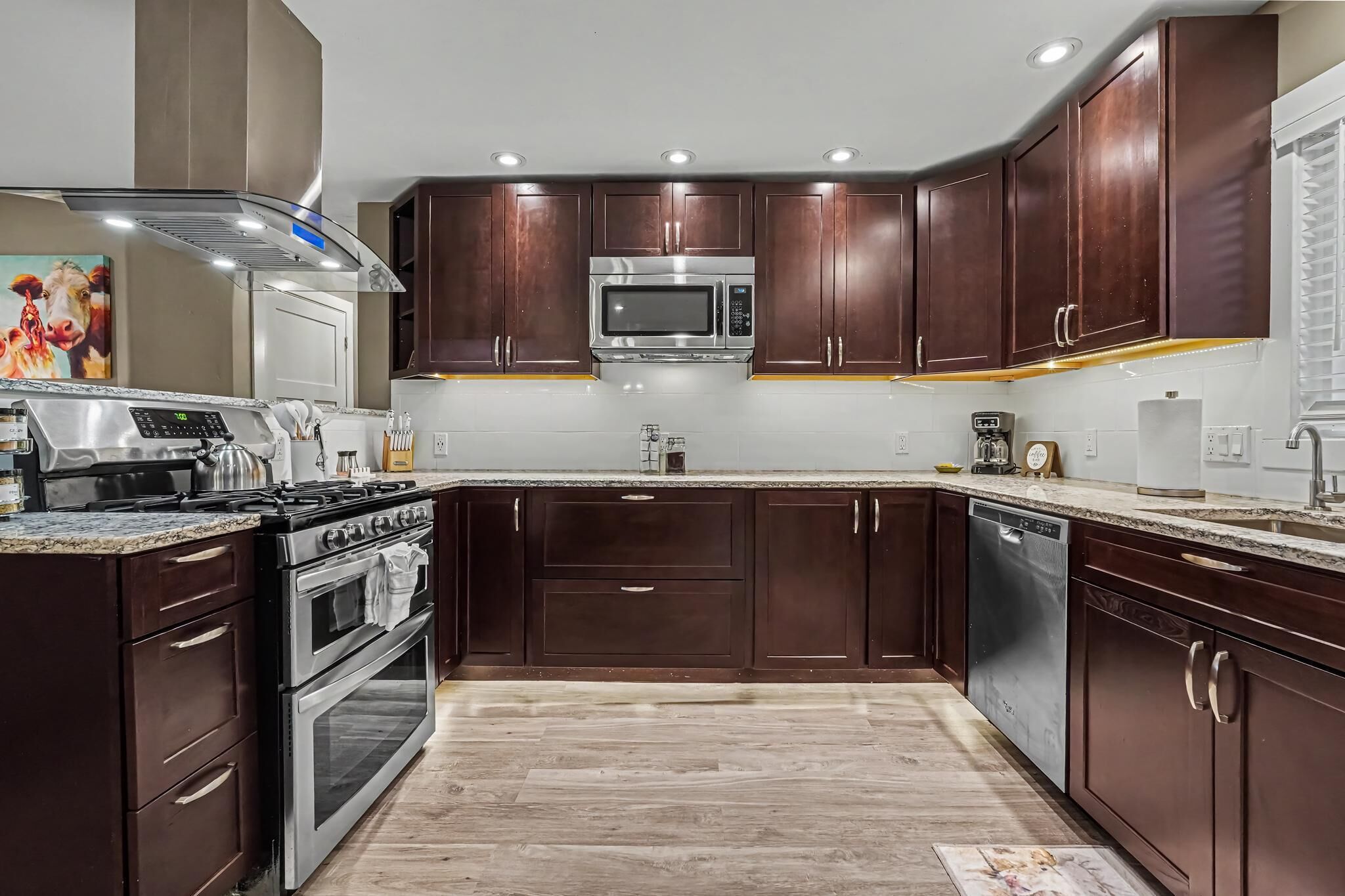 A modern kitchen with dark wood cabinets, stainless steel appliances, and a granite countertop.