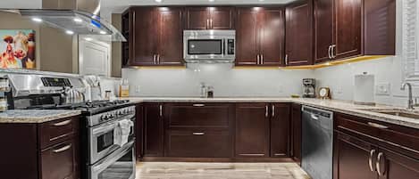 A modern kitchen with dark wood cabinets, stainless steel appliances, and a granite countertop.