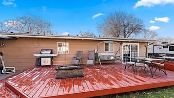 Une terrasse couverte équipée d’un barbecue, de sièges et d’un jacuzzi.