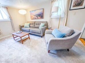 A living room with a sofa, a coffee table, a lamp, and a painting on the wall.
