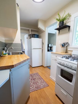 A compact kitchen with a microwave, refrigerator, stove, and sink.