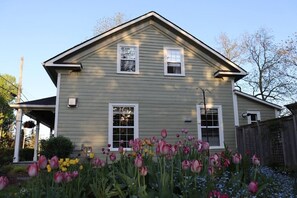 A two-story house with a gabled roof, a covered porch, and a front yard with tulips.