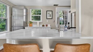 Una cocina moderna con una isla grande, electrodomésticos de acero inoxidable y vistas a zonas verdes.