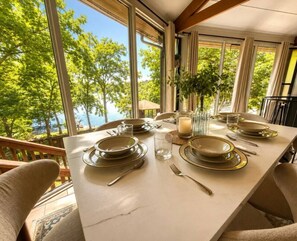 Spisebord dækket med tallerkener, glas og bestik, med udsigt til et smukt landskab.