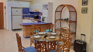 Una cocina compacta con refrigerador, microondas y estufa. Un comedor con sillas está dispuesto en la zona de estar.