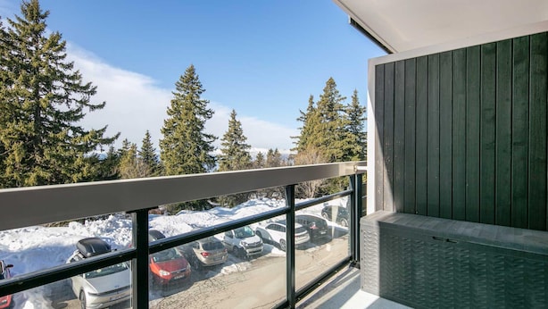 A balcony with a view of snow-covered ground and parked cars, overlooking a forested area. - Quiet Mountain Stay in Chamrousse (Chamrousse)