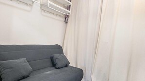 A grey sofa with two cushions, a white curtain, and a white wall. - Quiet Mountain Stay in Chamrousse (Chamrousse)