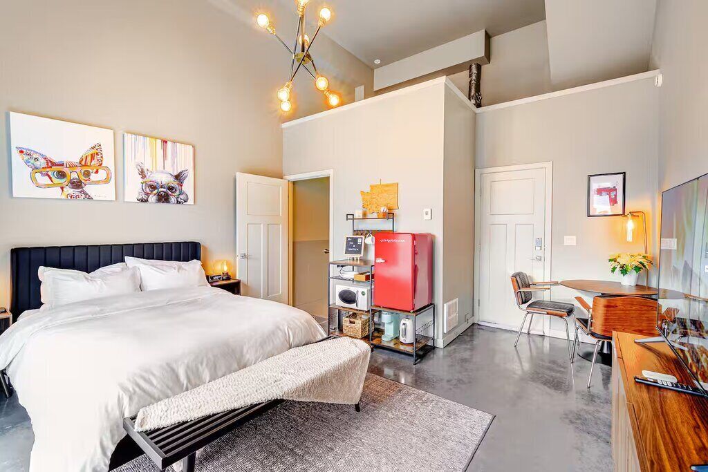 Een moderne hotelkamer met een groot bed, een bureau, een koffiezetapparaat en kunst aan de muren.