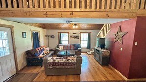 A cozy living room with a wooden ceiling, a sofa set, a television, and a staircase. - RiverBend Retreat
Cozy 1 bedroom, 2 loft cabin. (Leakey)