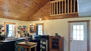 A rustic kitchen with wooden beams, a dining table, and a built-in cabinet. - RiverBend Retreat
Cozy 1 bedroom, 2 loft cabin. (Leakey)