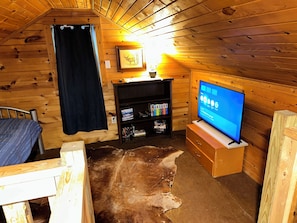 Ein gemütliches Blockhaus mit Fernseher, Bücherregal und einem Kuhfellteppich.
