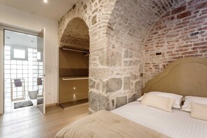 Ein Schlafzimmer mit Steinwand, einem Bett und einer Glastür zum Badezimmer.