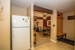 Eine Küche mit Kühlschrank, Esstisch aus Holz, Stühlen und Deckenventilator.