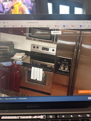 A MacBook Pro displaying a webpage with a kitchen layout including a stove, oven, and refrigerator. - HUGE DISCOUNT for last minute Beachfront  3-bedroom condo in beautiful Cruz Bay (Cruz Bay)
