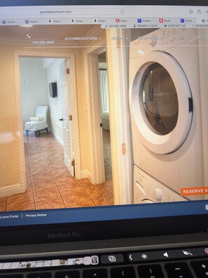 Ein Hotelzimmer mit Waschmaschine, einem Sessel und einer Tür zu einem weiteren Raum.